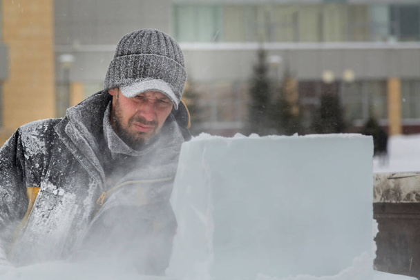 De beeldhouwer snijdt ijs contouren van ijs met een kettingzaag voor Kerstmis - Foto, afbeelding