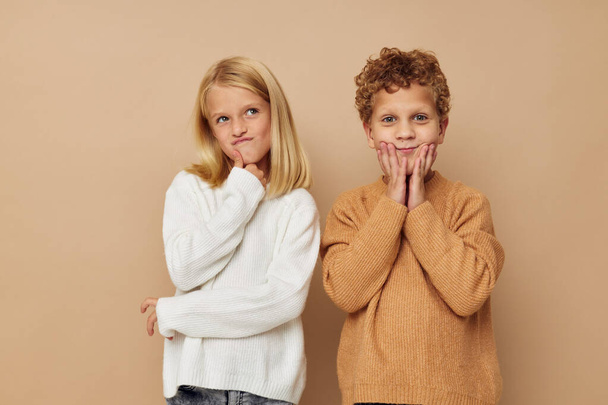 Boy and girl standing next to posing emotions beige background - Foto, Imagen