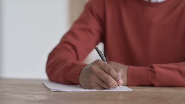 Handen close-up van de Afrikaanse man schrijven op papier - Video