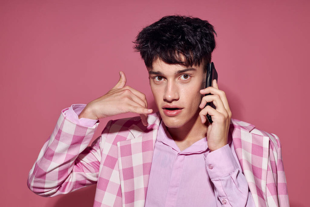 kaunis mies muodikas puhuminen puhelimessa vaaleanpunainen bleiseri poseeraa studio Lifestyle muuttamaton - Valokuva, kuva