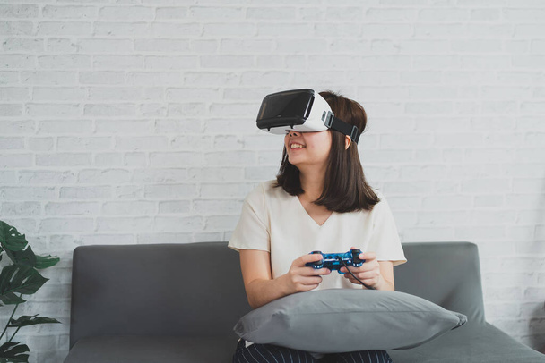 Aasian nainen pelata VR peli viihdyttää kotona, aasialainen nainen iloinen talossa lomalla. Onnellinen nainen pelaa metaverse VR teknologian käsite. - Valokuva, kuva