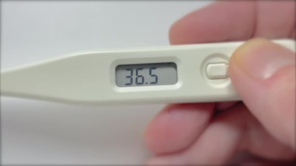 Electronic thermometer indicating temperature rise. Woman's hand holds digital medical thermometer with high temperature. Coronavirus symptom. - Footage, Video
