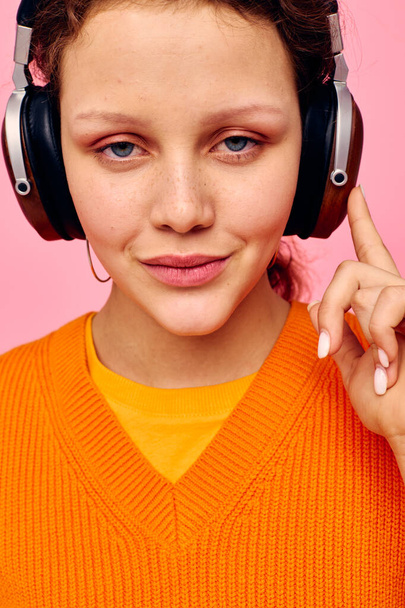 portrait of a young woman grimace headphones entertainment emotions music pink background unaltered - Valokuva, kuva