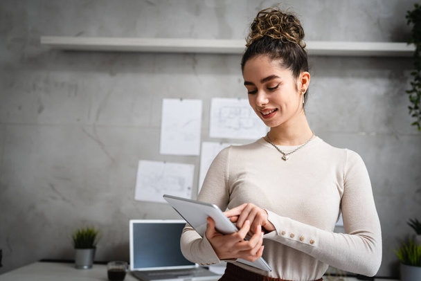 jedna žena mladá běloška bruneta šťastný úspěšný žena stojící v kanceláři v práci drží digitální tablet pas nahoru přední pohled kopírovat prostor - Fotografie, Obrázek