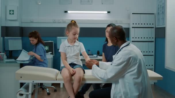 Πληγωμένο παιδί με τραυματισμένο χέρι που παρακολουθεί ιατρική γνωμάτευση - Πλάνα, βίντεο