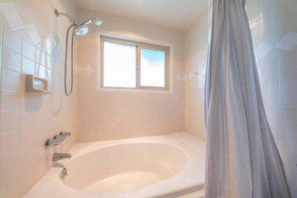 Wanna prysznicowa z beżowymi płytkami otaczającymi i montowanymi na ścianie podwójnymi głowicami prysznicowymi i baterią - Zdjęcie, obraz
