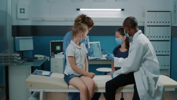 Různorodý lékařský tým zobrazující obraz lidské kostry na tabletu - Záběry, video