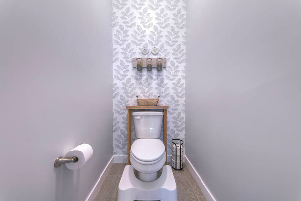 Pequeño cuarto de baño con taburete de paso blanco y soporte de papel higiénico montado en la pared - Foto, Imagen