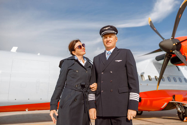 Pilote d'aéronef et hôtesse de l'air bras dans le bras à l'aéroport - Photo, image