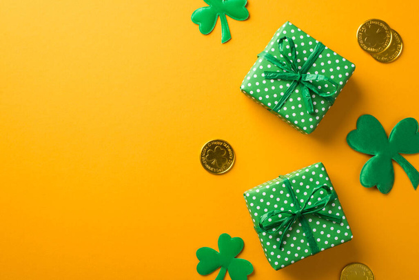 Top view photo of st patrick's day decorations two green gift boxes with polka dot pattern shamrocks and gold coins on isolated yellow background with empty space - Foto, imagen