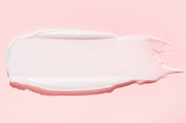 Smudge of organic antiaging cream professionele huidverzorging cosmetische product voor thuis en salon gebruik op roze sluiten bovenste aanzicht - Foto, afbeelding