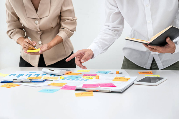 Деловые люди команда, босс держит книгу и указывая данные на стол, чтобы объяснить о новом бизнес-проекте в то время как деловая женщина пишет ключевое слово на почте это отмечает во время встречи в офисе - Фото, изображение