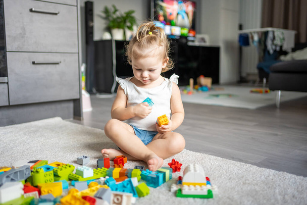 Bělošské dítě, malé děvčátko si hraje doma u konstruktéra. Vzdělávací hračky pro děti. - Fotografie, Obrázek