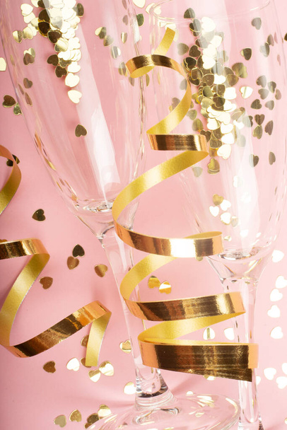 Valentines day champagne flutes glasses and heart shaped gold glitters on pink background - Valokuva, kuva