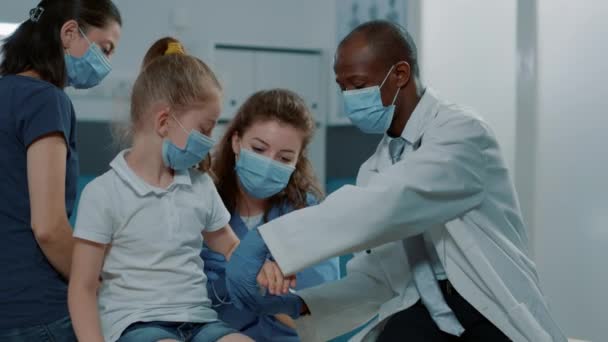 Equipo médico diverso que aplica bandaid en niño con brazo fracturado - Metraje, vídeo
