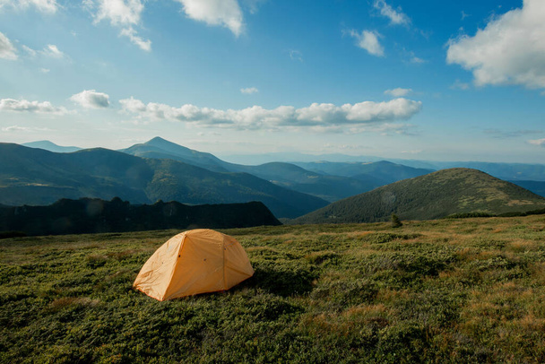 view of tourist tent in mountains at sunrise or sunset. Camping background. Adventure travel active lifestyle freedom concept. Summer vacation - Photo, image
