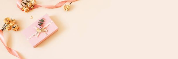 Hermosa caja de regalo rosa con rosas secas flores y cintas sobre fondo pastel. Regalo para vacaciones, cumpleaños, boda, día de la madre, día de San Valentín, día de la mujer. Copiar espacio. Vista superior, cama plana. Banner - Foto, Imagen