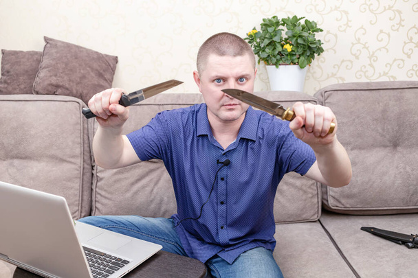Un homme en chemise bleue blogue sur les couteaux et les armes tranchantes - Photo, image