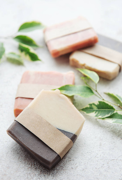 Assorted handmade soap bars and green leaves  - Foto, Imagen