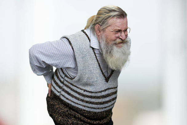 Öreg ember szürke szakáll szenved hátfájás homályos háttér. - Fotó, kép