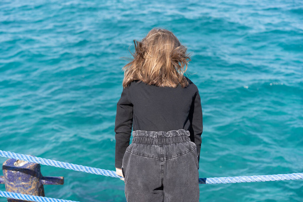 little girl on the pier near the sea in jeans - Foto, Imagem