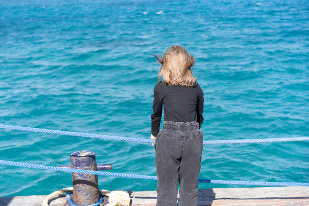 маленька дівчинка на пірсі біля моря в джинсах
 - Фото, зображення