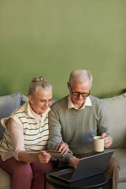Rento vanhempi mies ja nainen istuu sohvalla edessä kannettavan - Valokuva, kuva