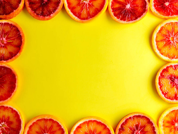 黄色の背景に単離された明るい赤血オレンジ果実スライスからのフレーム.フラットレイアウト、トップビュー、コピースペース - 写真・画像