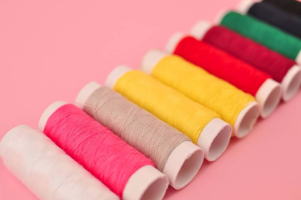 Multicolored threads for sewing on pink background . High quality photo - Foto, Imagem
