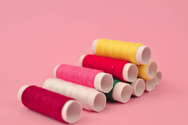 Hilos multicolores para coser sobre fondo rosa. Foto de alta calidad - Foto, imagen