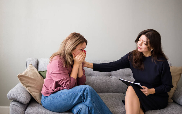 the psychologist woman put her hand on the shoulder of the upset woman patient. A gesture of support. Psychological assistance to a woman - Foto, immagini