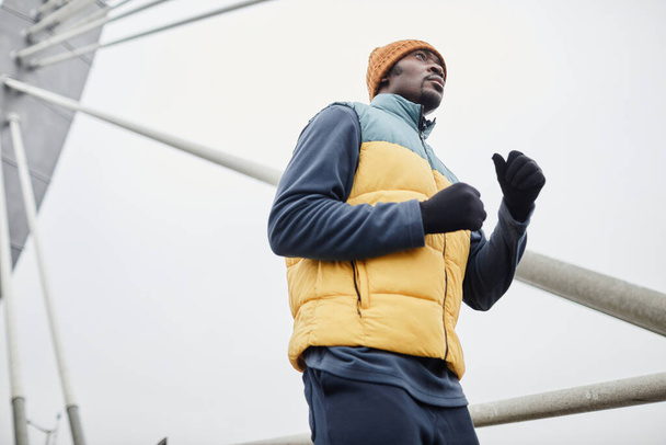 Mladý černoch ve sportovním oblečení a rukavice běží v městském prostředí - Fotografie, Obrázek