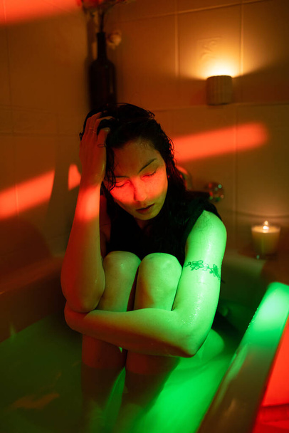 Μια καταθλιπτική Ασιάτισσα κάθεται στο μπάνιο με κρύο νερό σκέφτεται το πρόβλημα του έρωτα, διαλύει ή καταστρέφει το γάμο - Φωτογραφία, εικόνα