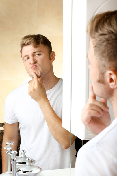 Young man shaving his beard in bathroom - Foto, imagen