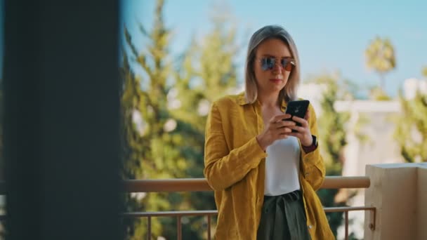 Žena chatování přes smartphone na balkóně v létě. - Záběry, video