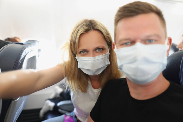 Young family couple in protective masks on the plane - Foto, imagen