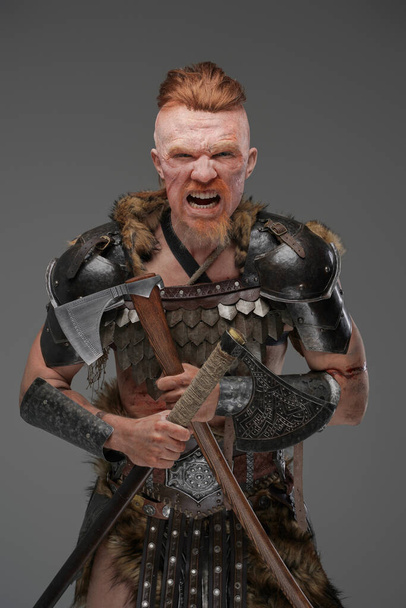 Screaming antique viking with two axes against gray background - Photo, Image