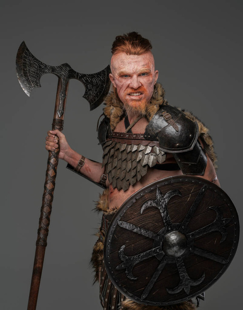 Barbaric viking warrior wielding axe and shield isolated on gray - Фото, изображение