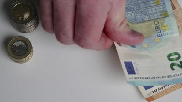 Hand of European man counting euro bank notes and euro coins on white desk with 10, 20 euro and 50 euro banknotes as income for financial investment and capital of crowd funding salary stack trade - Footage, Video
