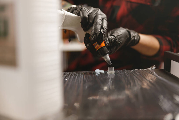 Закрытие татуировщика, готовящего инструменты и чернила перед работой - Фото, изображение