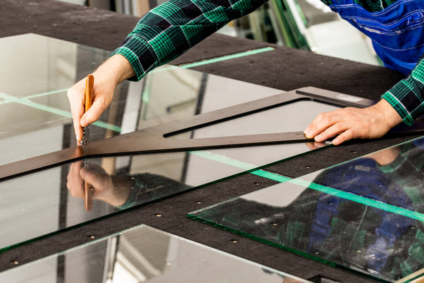 Le vitrier coupe le verre dans l'usine de verre, le cutter et l'angle de verre  - Photo, image