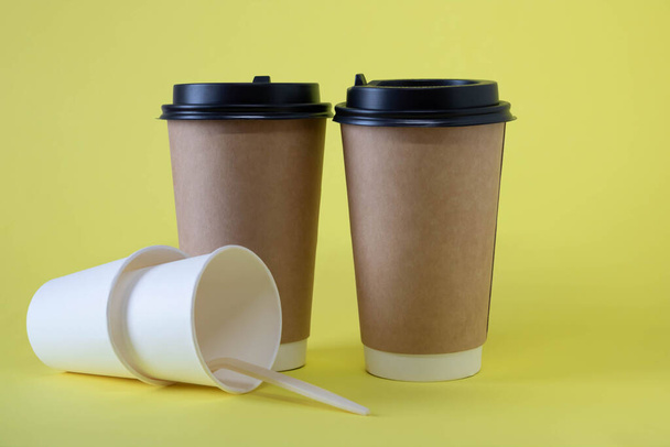 Δύο καφέ και δύο λευκά ποτήρια σε κίτρινο φόντο. - Φωτογραφία, εικόνα