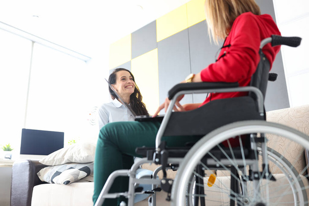 Kobieta na wózku inwalidzkim komunikuje się z przyjacielem w domu zbliżenie - Zdjęcie, obraz