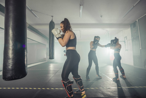 Boxer woman. Boxing fitness woman smiling happy wearing black boxing gloves. Portrait of sporty fit Asian model of boxing gym - Foto, afbeelding