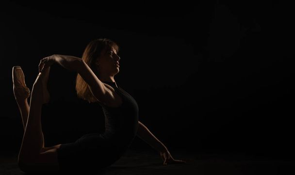 Ballerina bereitet sich in Silhouette auf ihre perfekte Pose am Boden vor - Foto, Bild