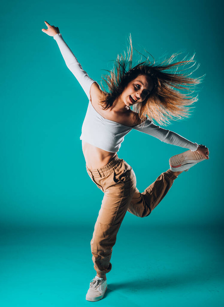 Caucasian female dancer exercising a contemporary dancing against blue wall - Zdjęcie, obraz
