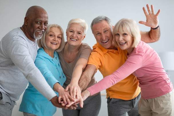 Wielorasowa grupa wysportowanych seniorów wkładających ręce - Zdjęcie, obraz