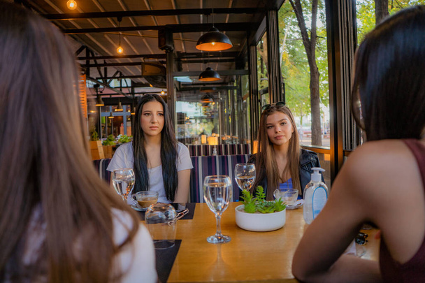 Neljä upeaa ja kaunista tyttöä keskustelevat kahvilassa. - Valokuva, kuva