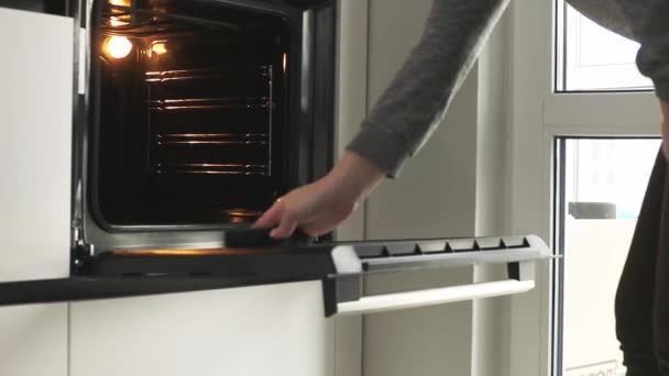 Nainen puhdistaa sähköuuni ruoanlaiton jälkeen - Materiaali, video