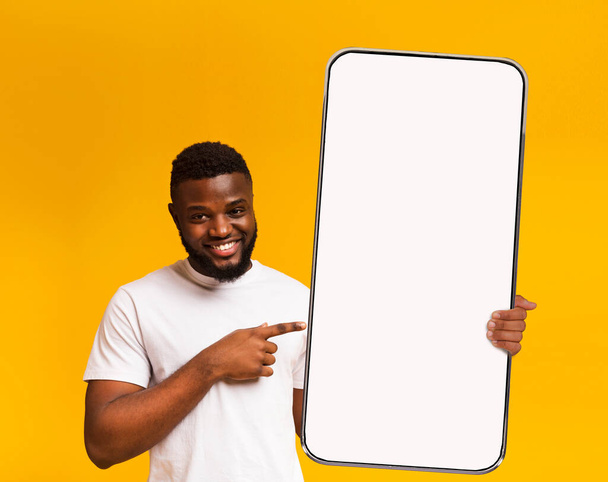Chico negro apuntando a la pantalla del teléfono inteligente blanco vacío - Foto, Imagen